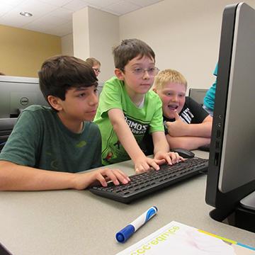 three young boys working at a computer